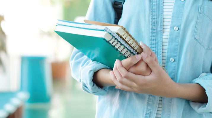 image of a woman holding notebooks for the our faculties section